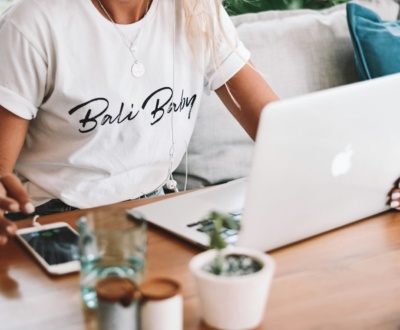 woman in white crew neck t-shirt sitting by the table with macbook